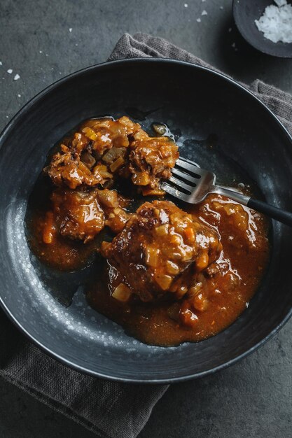 Beef stew ball with vegetable feeling in sauce on dark plate. Closeup