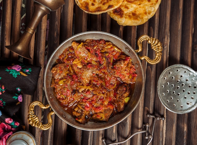 Free photo beef stew in tomato sauce inside copper pan.