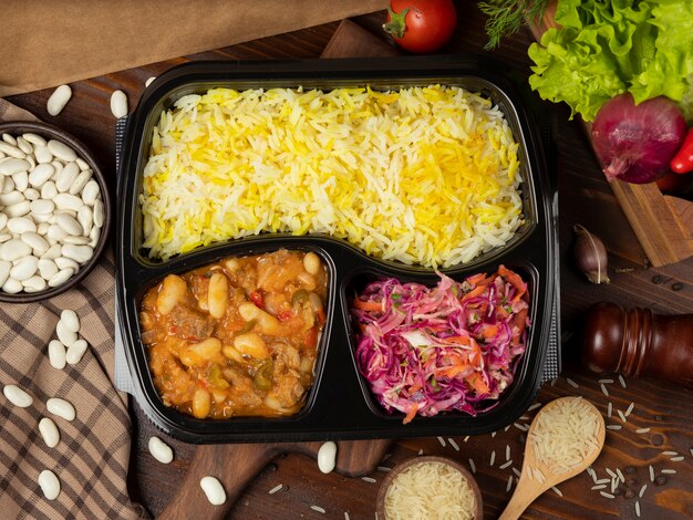 Beef stew with potato and chestnuts in tomato sauce with rice garnish and cabbage carrot salad takeaway   