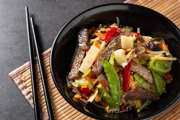 Free photo beef, vegetables and sesame seeds in black bowl on black slate background