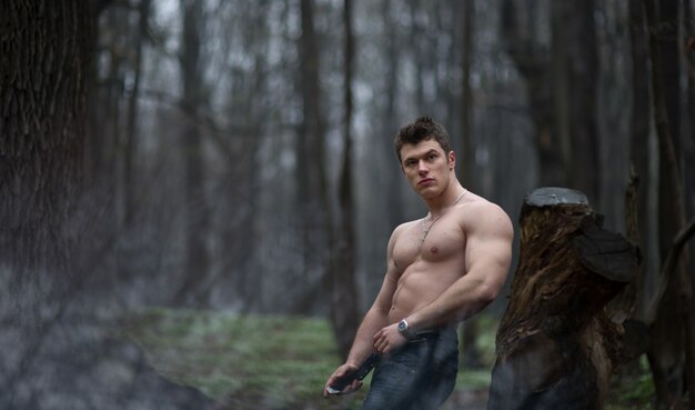 "Beefy man posing in woods"
