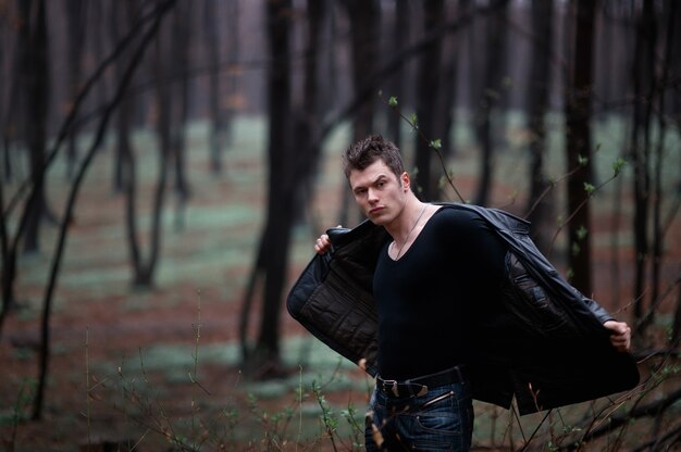 "Beefy man taking off jacket in woods"