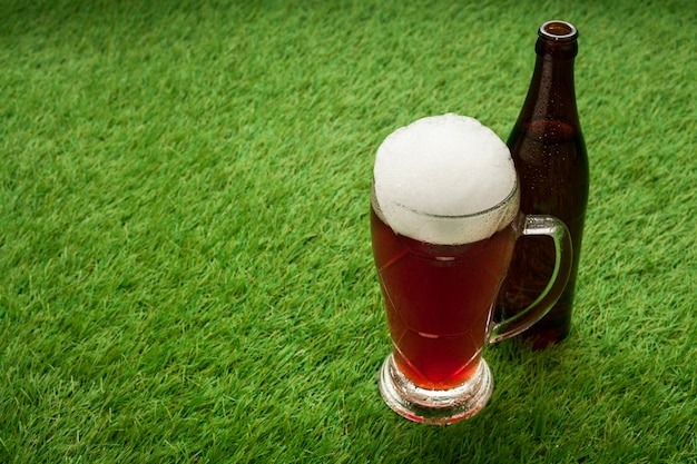 Beer bottle and glass on grass with copy space