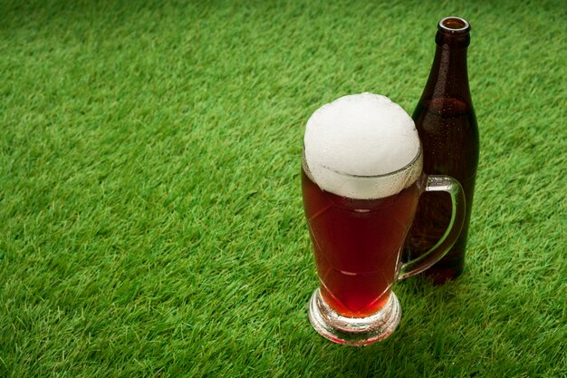 Beer bottle and glass on grass with copy space