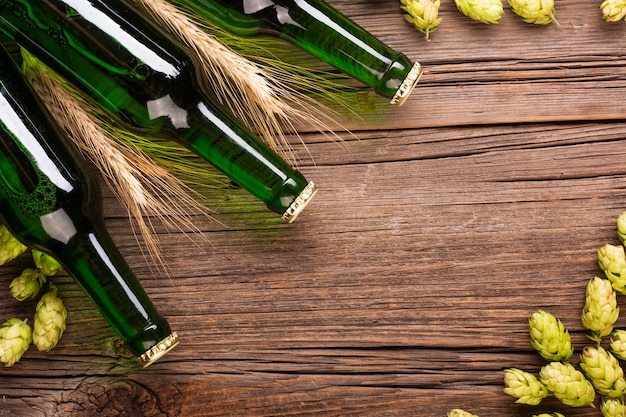 Beer bottles and ingredients of beer on wooden background
