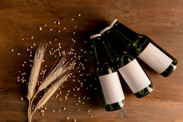 Beer bottles in white label with wheat spike on wooden table