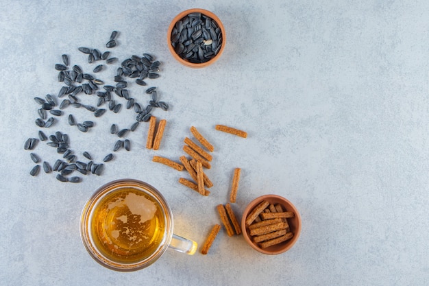 Free photo beer glass and bowl of croutons chickpea, seed , on the marble background.