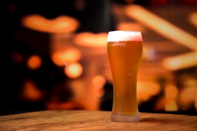 Foto gratuita bicchiere di birra davanti a sfondo sfocato