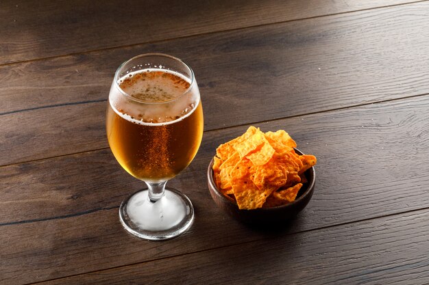 Пиво в бокале с чипсами под высоким углом зрения на деревянном столе
