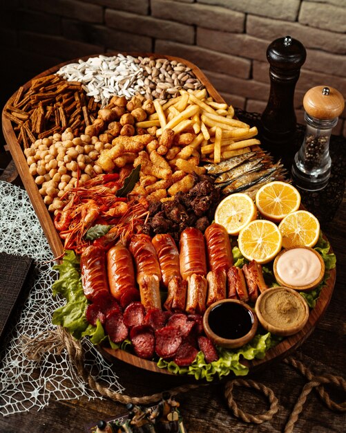 Beer snacks platter with shrimps sausages chickpeas fried cheese french fries sunflower seeds and lemon