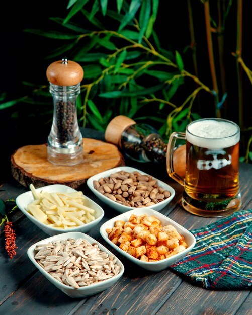 Beer with foam pistachios crackers cheese and seeds