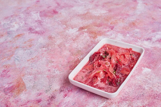 Beetroot and cabbage soup in a white saucer.