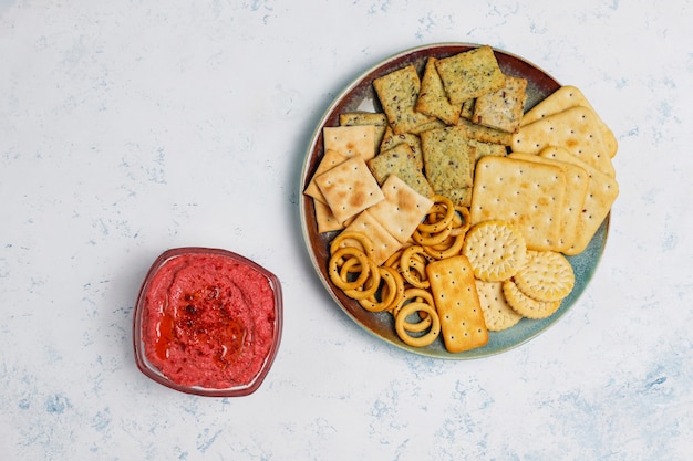 明るい表面に塩味のクッキーとまな板の上のビートルートフムス