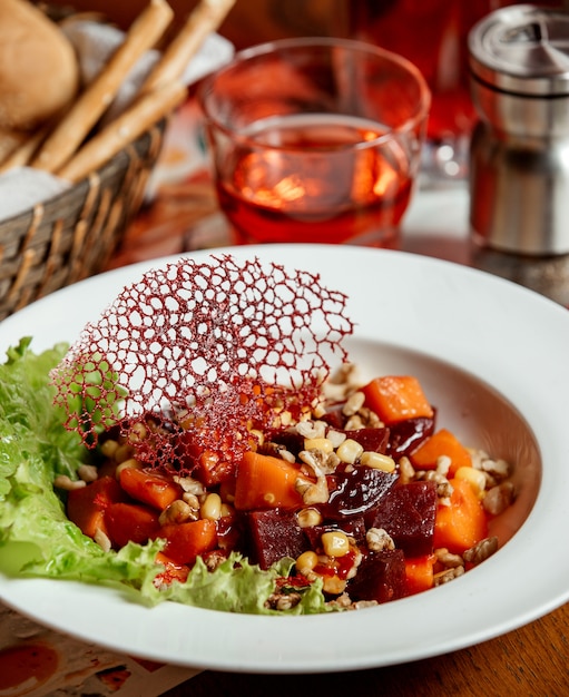 Beetroot salad with carrots, corn and nuts in a white plate
