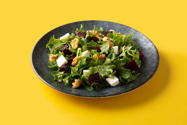 Beetroot salad with feta cheese,lettuce and walnuts on yellow backgrund