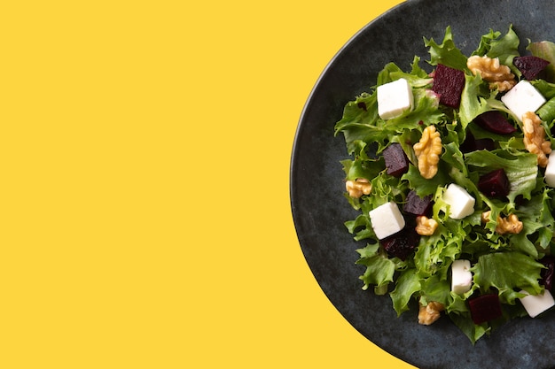 Beetroot salad with feta cheese,lettuce and walnuts on yellow backgrund