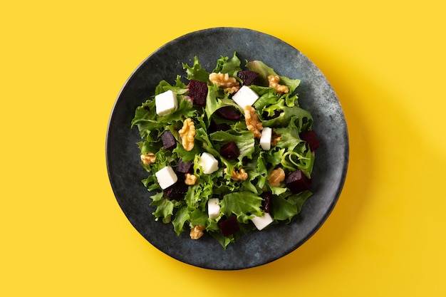 Beetroot salad with feta cheese,lettuce and walnuts on yellow backgrund