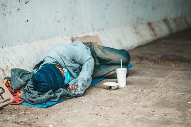 Beggars lying on the side of the street with dirty clothes.