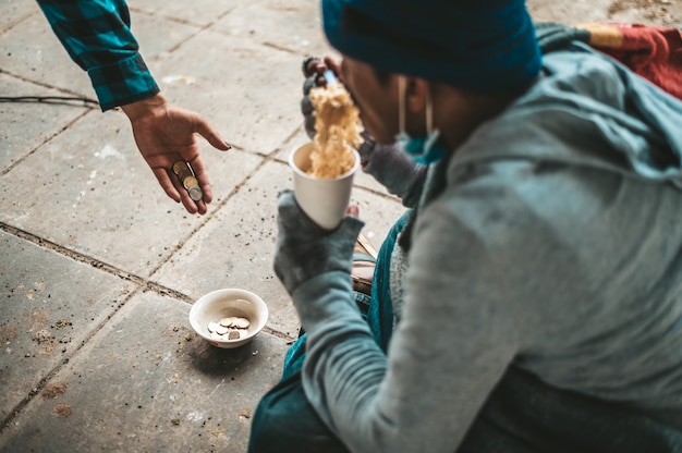 Foto gratuita i mendicanti sedevano avvolti in panni e mangiavano noodles.