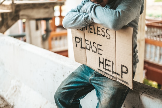 Free photo beggars sit on barriers with homeless please help messages.