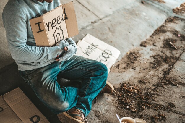 Beggars sitting under the bridge with a sign, please home.