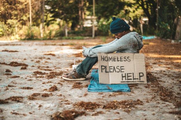 Free photo beggars sitting on the street with homeless messages please help.