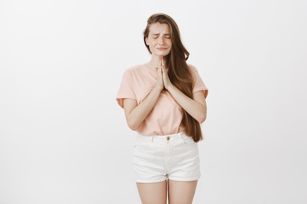 Begging cute teenage girl posing against the white wall