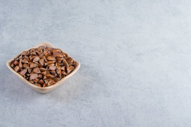돌 배경에 많은 바삭바삭한 씨앗의 베이지색 그릇.
