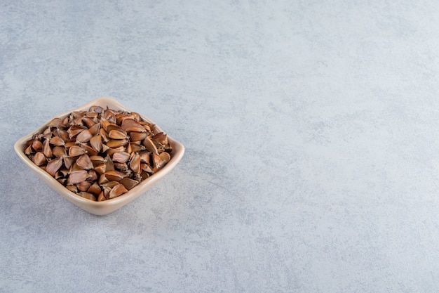 Beige bowl of many crunchy seeds on stone background.