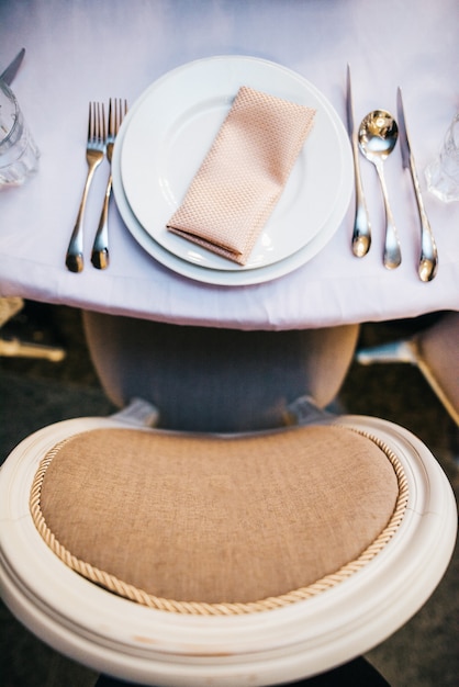 ベージュの椅子、白い皿で夕食のテーブルに立つ