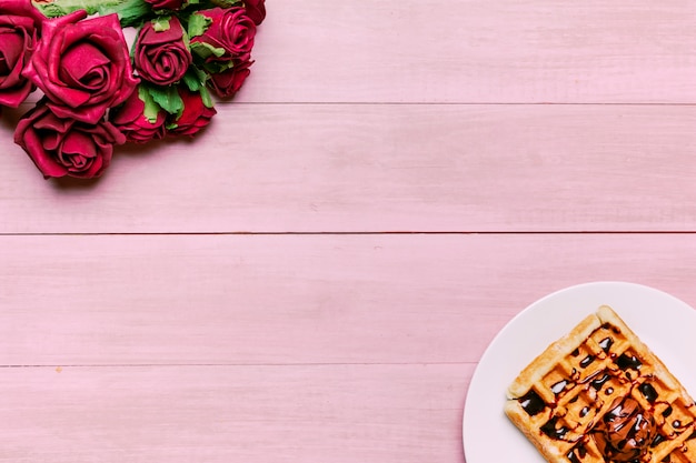 Belgian waffle with red roses bouquet on table