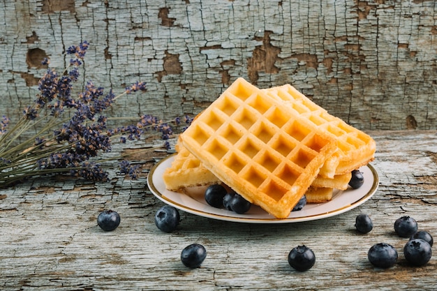 Belgian waffles near blueberries and bouquet