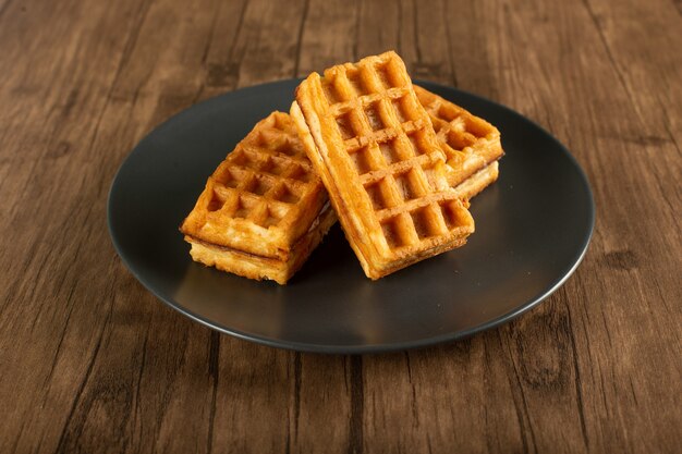 Belgian waffles in a saucer on a wooden table.