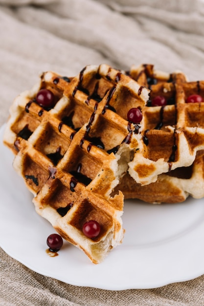 Free photo belgian waffles with berry and chocolate syrup on white plate