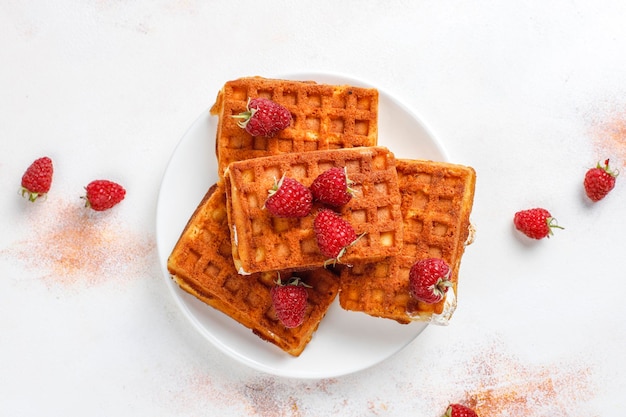 Belgian waffles with cream and fresh raspberries.