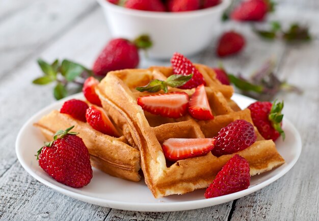 Belgium waffles with strawberries and mint  on white plate