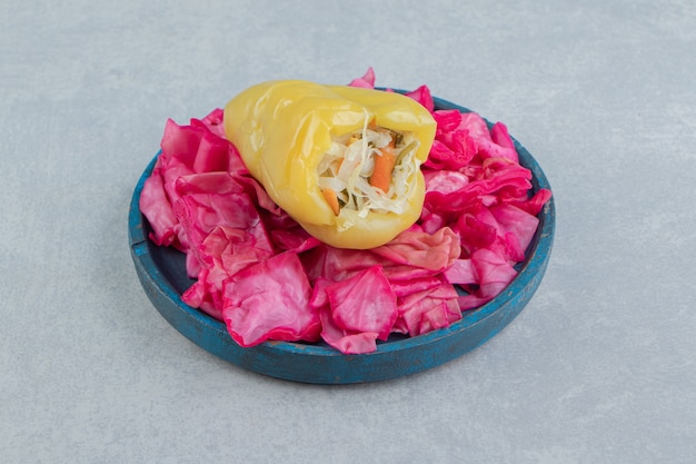 Bell pepper and sliced red cabbage on the wooden plate on the marble surface