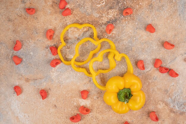 Bell pepper slices and red pasta on orange background