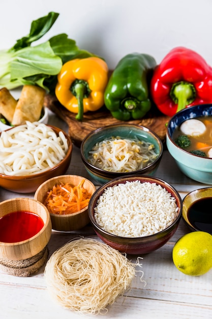 Bell peppers; sprout beans; rice; udon noodles; sauces and dry rice vermicelli on white desk