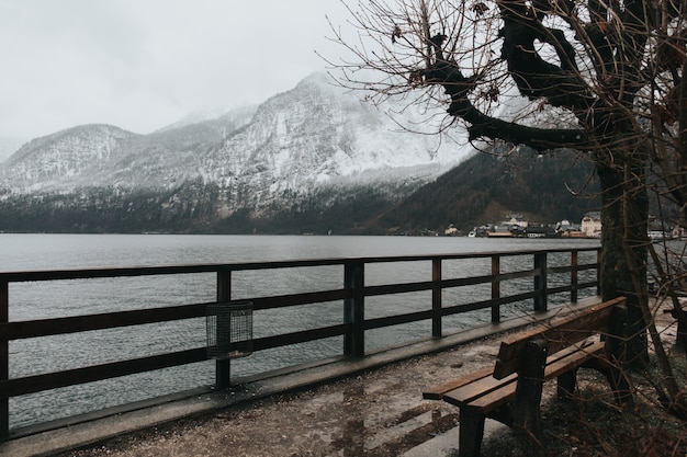 Bench near the lake on a cold day and snowy mountains