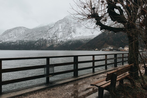 寒い日に湖の近くのベンチと雪山