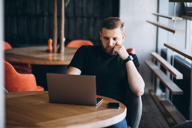 Beraded man working on laptop in a cafe