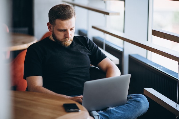 Beraded man working on laptop in a cafe