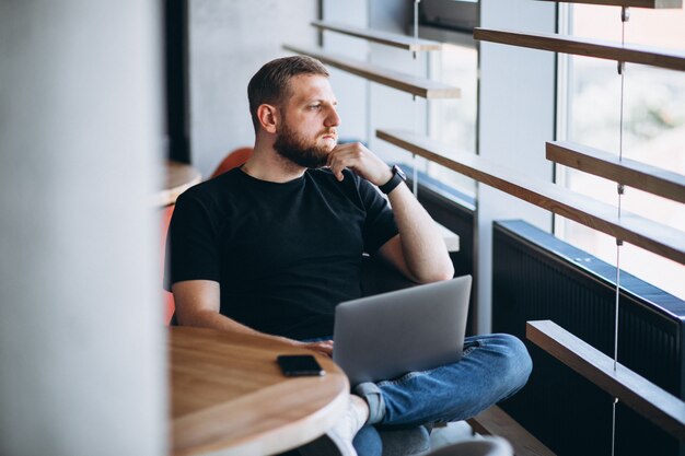 Beraded man working on laptop in a cafe