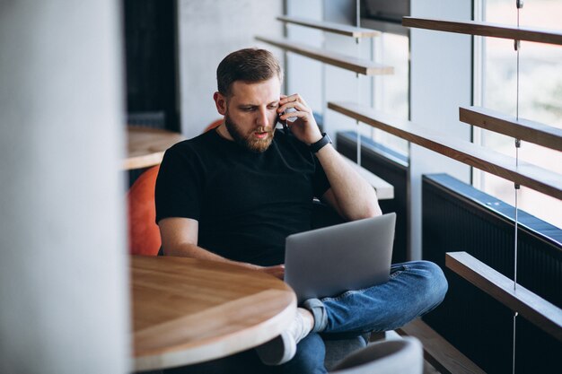 Beraded man working on laptop in a cafe