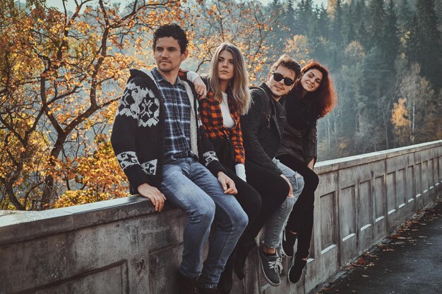 Best friends are posing for photographer while walking in autumn forest.