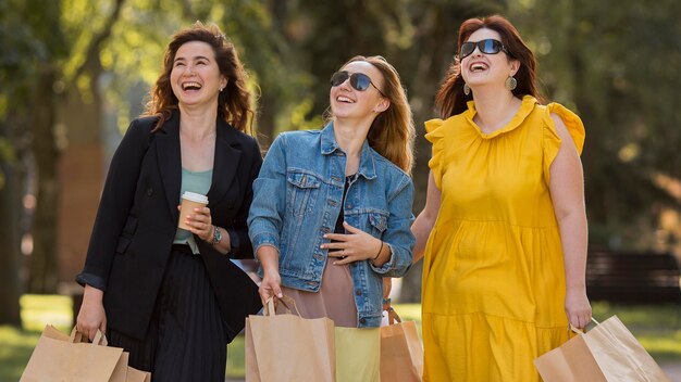 Best friends chatting while walking in the park with shopping bags