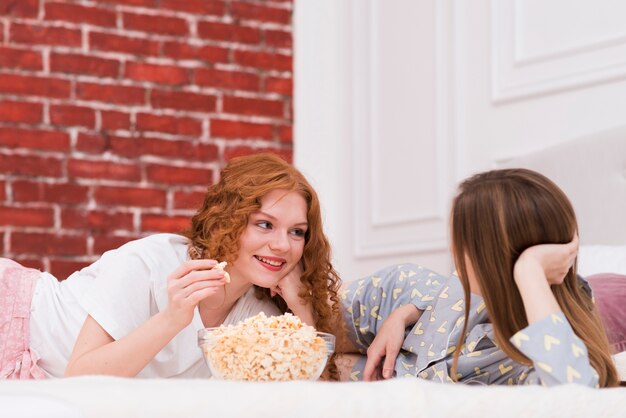 Best friends eating popcorn while in bed