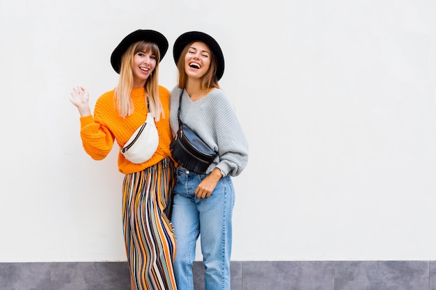 Best friends  embracing , couple of  stylish girls posing on white