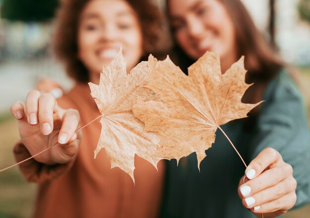 Best friends holding autumn leaves